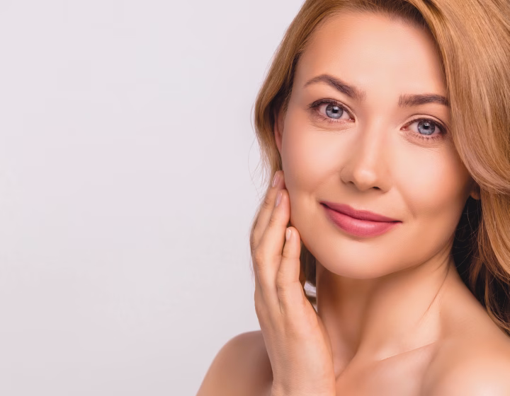 Woman with clear skin resting a hand against her cheek